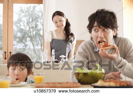 Stock Photo - Mother Watching Father and Son Playing at Dinner Table. Fotosearch