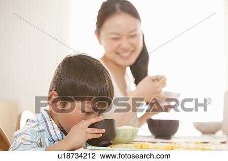 Stock Image - Mother Watching Son Eating Soup. Fotosearch
