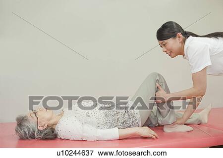 Nurse helping a senior woman stretch, Kanagawa Prefecture, Honshu, Japan View Large Photo Image Stock Photo - Nurse helping a senior woman stretch, Kanagawa Prefecture, Honshu, Japan. Fotosearch