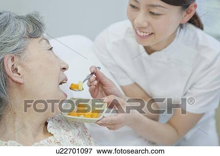 Nurse helping up a senior woman eat in bed, Kanagawa Prefecture, Honshu, Japan View Large Photo Image Stock Photo - Nurse helping up a senior woman eat in bed, Kanagawa Prefecture, Honshu, Japan. Fotosearch