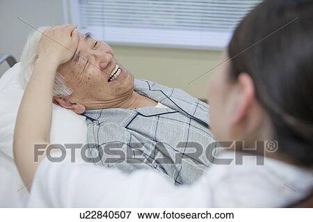 Stock Photo - Nurse taking senior man's temperature, Kanagawa Prefecture, Honshu, Japan. Fotosearch