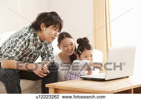 Stock Image - Parents and Daughter Using Laptop. Fotosearch