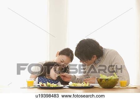 Stock Image - Parents Feeding Baby Girl. Fotosearch