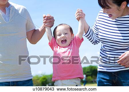 Stock Image - Parents Lifting Little Boy From Hands. Fotosearch