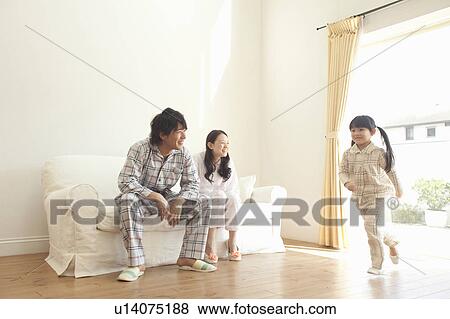 Stock Photo - Parents Watching Daughter Running in Living Room. Fotosearch