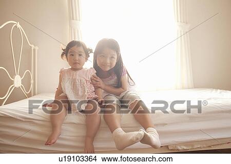 Picture - Portrait of Two Sisters Sitting on Bed. Fotosearch