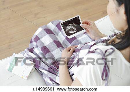 Stock Image - Pregnant Woman Looking at Ultrasaound Scan. Fotosearch