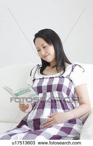 Stock Image - Pregnant Woman Reading Picture Book. Fotosearch