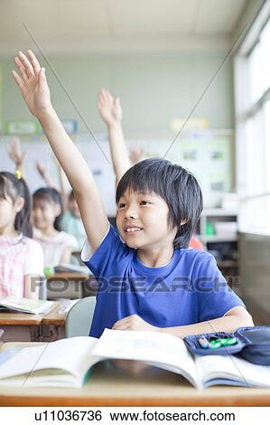 Stock Photograph - Schoolboy Raising Hand in Classroom. Fotosearch