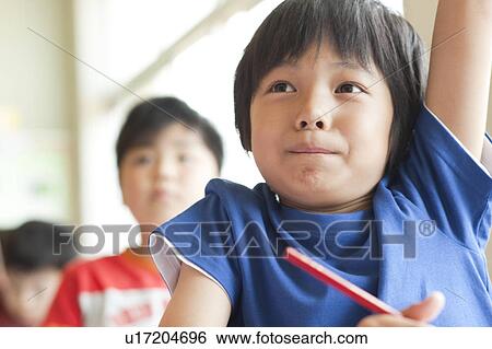 Stock Photograph - Schoolboy Raising Hand in Classroom. Fotosearch