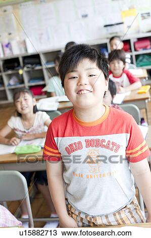 Stock Image - Schoolboy Standing in Classroom. Fotosearch