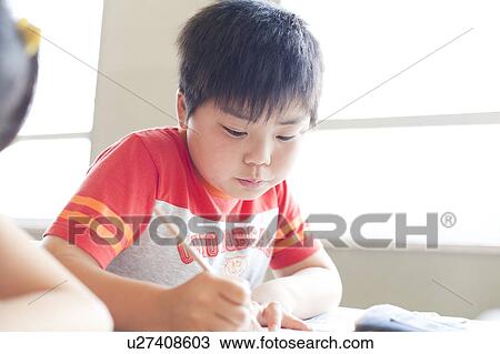 Stock Image - Schoolboy Writing Studying concentration. Fotosearch