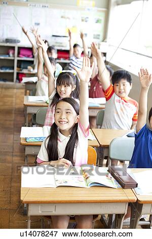 Stock Photo - Schoolchildren Raising Hands in Classroom. Fotosearch