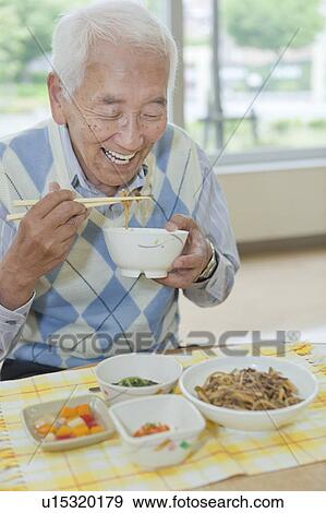 Stock Photo - Senior man eating food, Kanagawa Prefecture, Honshu, Japan. Fotosearch