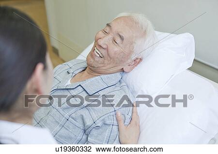 Senior man lying on bed talking to nurse, Kanagawa Prefecture, Honshu, Japan View Large Photo Image Stock Image - Senior man lying on bed talking to nurse, Kanagawa Prefecture, Honshu, Japan. Fotosearch