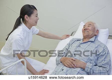 Senior man lying on bed talking to nurse, Kanagawa Prefecture, Honshu, Japan View Large Photo Image Stock Photo - Senior man lying on bed talking to nurse, Kanagawa Prefecture, Honshu, Japan. Fotosearch