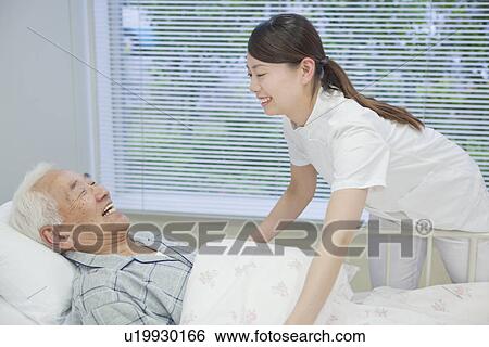 Senior man lying on bed talking to nurse, Kanagawa Prefecture, Honshu, Japan View Large Photo Image Stock Photograph - Senior man lying on bed talking to nurse, Kanagawa Prefecture, Honshu, Japan. Fotosearch