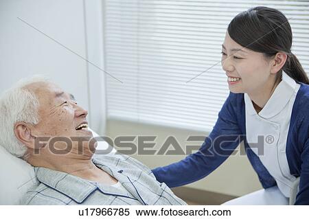 Senior man lying on bed talking to nurse, Kanagawa Prefecture, Honshu, Japan View Large Photo Image Stock Photography - Senior man lying on bed talking to nurse, Kanagawa Prefecture, Honshu, Japan. Fotosearch
