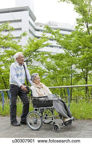 Senior man pushing senior woman on wheelchair, Kanagawa Prefecture, Honshu, Japan View Large Photo Image Stock Image - Senior man pushing senior woman on wheelchair, Kanagawa Prefecture, Honshu, Japan. Fotosearch
