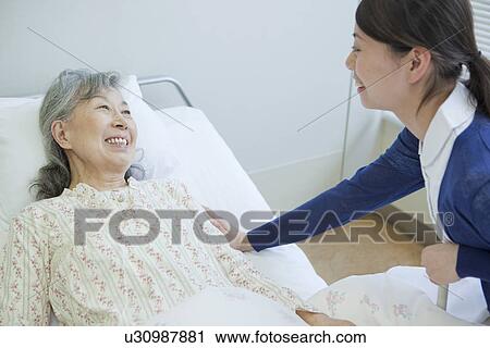 Senior woman lying on bed talking to nurse, Kanagawa Prefecture, Honshu, Japan View Large Photo Image Stock Image - Senior woman lying on bed talking to nurse, Kanagawa Prefecture, Honshu, Japan. Fotosearch