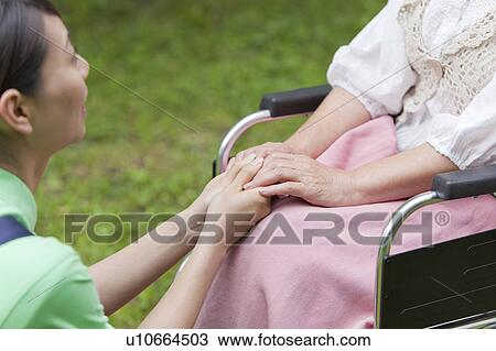 Stock Image - Social Worker Holding Senior Woman's Hands. Fotosearch