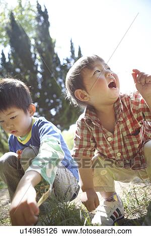 Stock Photograph - Two Boys Crouching in Grass. Fotosearch