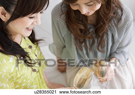 Stock Image - Two Female Friends Toasting with Champagne. Fotosearch