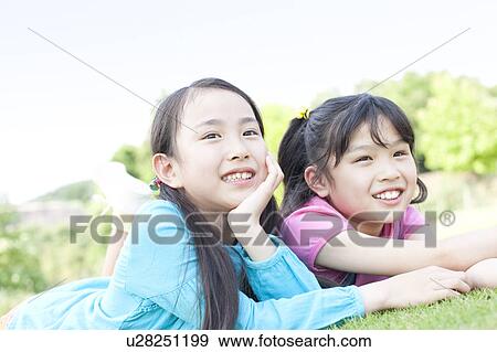 Stock Photo - Two Girls Lying on Grass. Fotosearch