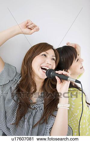 Stock Image - Two Women Singing Karaoke and Having Champagne. Fotosearch