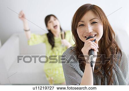 Stock Photo - Two Women Singing Karaoke and Having Champagne. Fotosearch