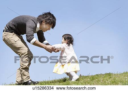 Picture - Young Father Holding Baby Girl's Hands. Fotosearch