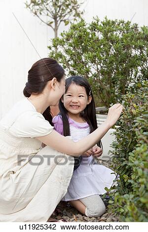 Stock Image - Young Mother and Daughter in Garden. Fotosearch