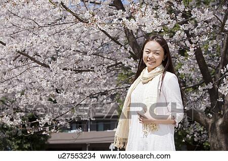 Picture - Young Woman Against Cherry Blossoms. Fotosearch