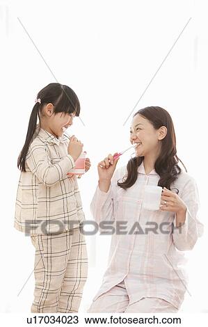 Stock Image - Young Woman and Daughter Brushing Teeth. Fotosearch