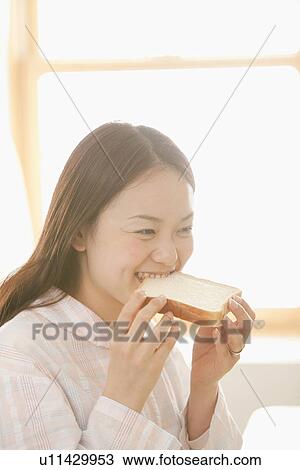 Stock Image - Young Woman Eating Slice of Bread. Fotosearch