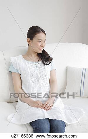 Stock Photograph - Young Woman Sitting on Sofa. Fotosearch