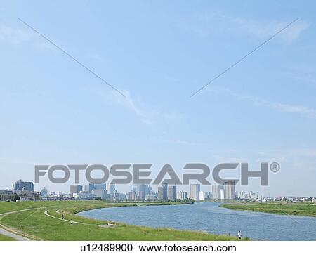 Stock Image - Blue Sky Over City, Grass in Foreground. Fotosearch