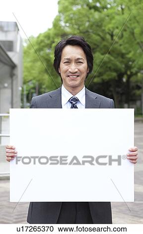 Stock Image - Businessman holding a blank board. Fotosearch