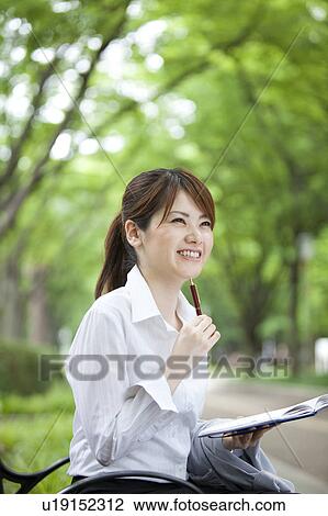 Stock Image - Businesswoman sitting on park bench . Fotosearch
