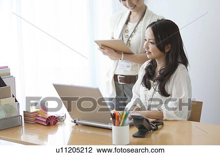 Businesswomen having a meeting in front of a laptop View Large Photo Image Stock Image - Businesswomen having a meeting in front of a laptop. Fotosearch