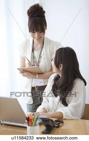 Businesswomen having a meeting in front of a laptop View Large Photo Image Stock Image - Businesswomen having a meeting in front of a laptop. Fotosearch