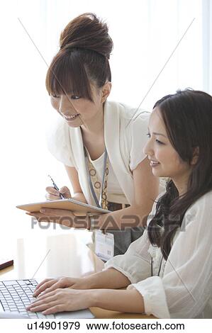Businesswomen having a meeting in front of a laptop View Large Photo Image Stock Photo - Businesswomen having a meeting in front of a laptop. Fotosearch