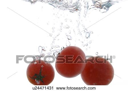 Stock Image - Cherry tomatoes falling into water. Fotosearch