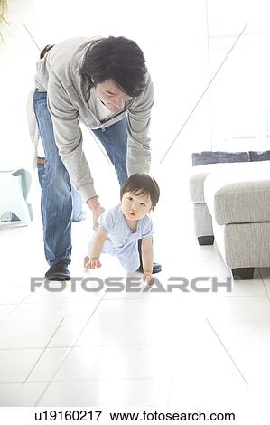 Stock Photo - Father Helping Baby Boy to Crawl. Fotosearch