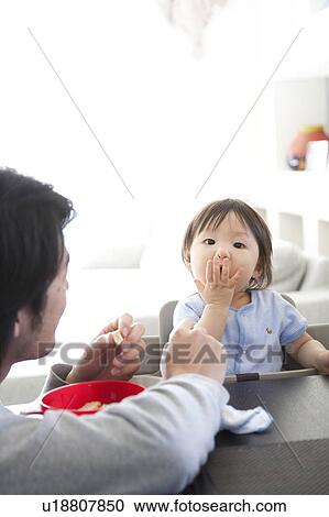 Stock Image - Father Watching Baby Boy Eating. Fotosearch
