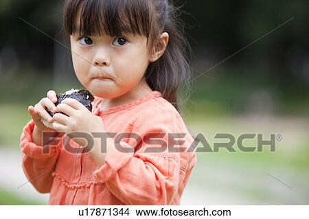 Picture - Girl eating rice ball. Fotosearch