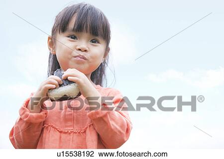 Stock Image - Girl eating rice ball. Fotosearch