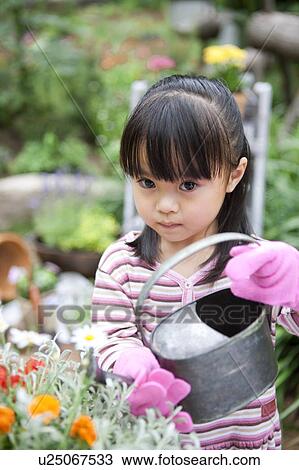 Girl watering potted flower View Large Photo Image Stock Image - Girl watering potted flower. Fotosearch