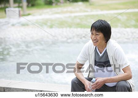 Man sitting by a fountain holding bottled water View Large Photo Image Stock Image - Man sitting by a fountain holding bottled water. Fotosearch