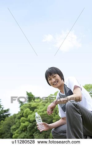 Mature man holding bottled water and looking at camera View Large Photo Image Stock Photo - Mature man holding bottled water and looking at camera. Fotosearch